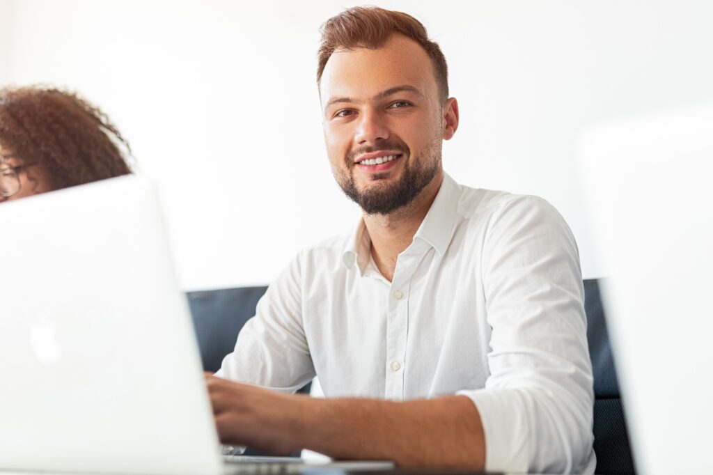 Office employee with laptop smiling for camera